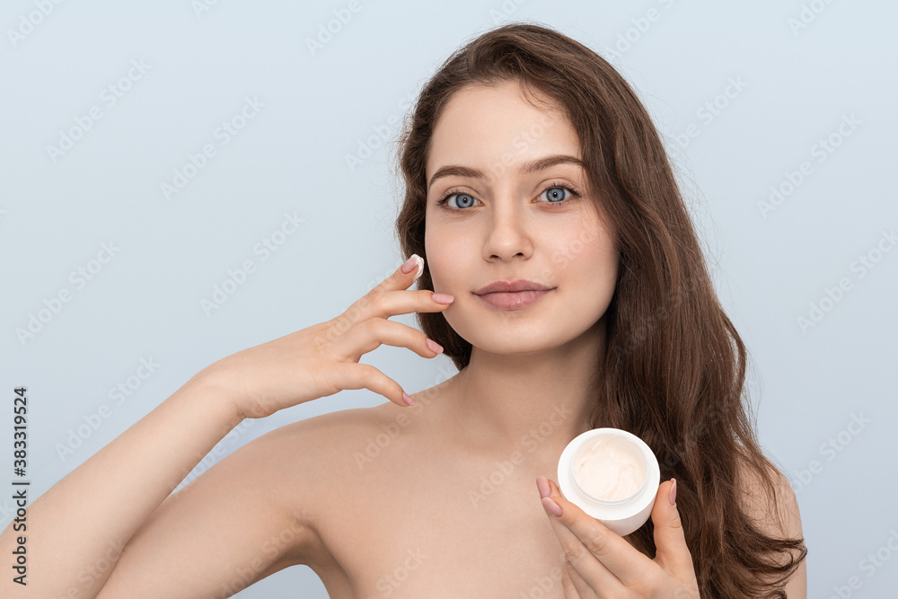 Portrait of young woman applying moisturizer cream on her face. Portrait of young woman applying moisturizer cream on her face.