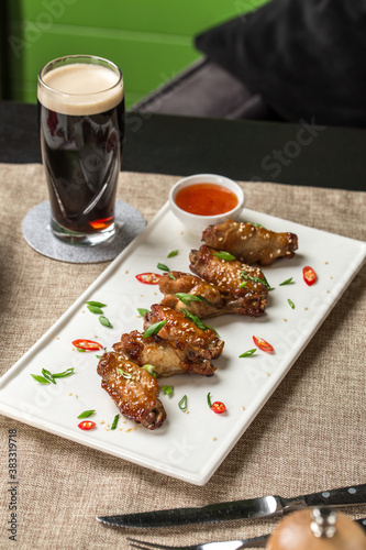 Chicken wings with sesame seeds and glass of dark beer on the table at restaurant photo