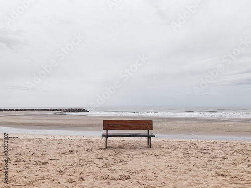 Wooden fence on sand beach with cloudy sky