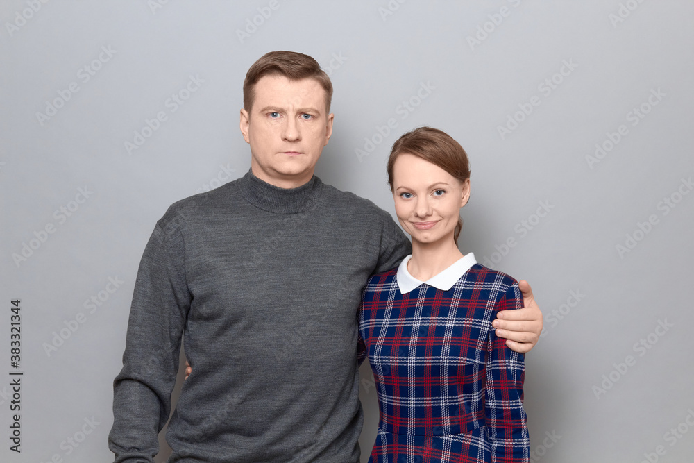 Portrait of serious man and joyful woman hugging each other Portrait of serious man and joyful woman hugging each other