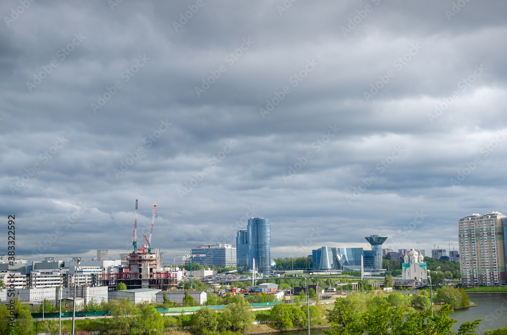 Obraz premium New buildings against the backdrop of a dramatic sky. greenery and water with a running motorway