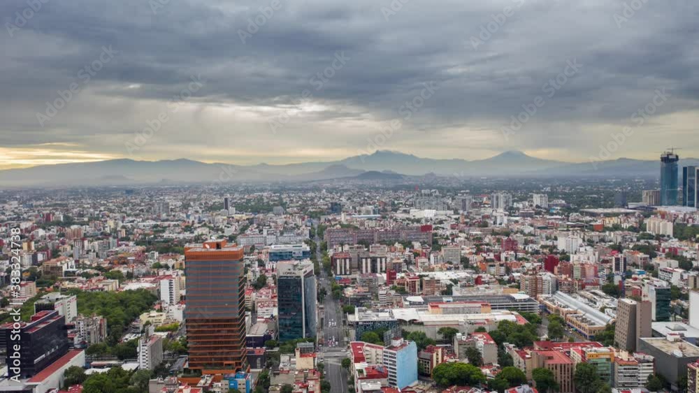 Dramatic hyperlapse of an overcast mexico city with cloud movement and 2 volcanoes as foreground, one of which has snow