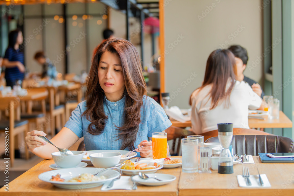 Asian woman is having breakfast relaxing drinking fresh juice, Boiled rice with pork at breakfast buffet in hotel. Asian woman is having breakfast relaxing drinking fresh juice, Boiled rice with pork at breakfast buffet in hotel.