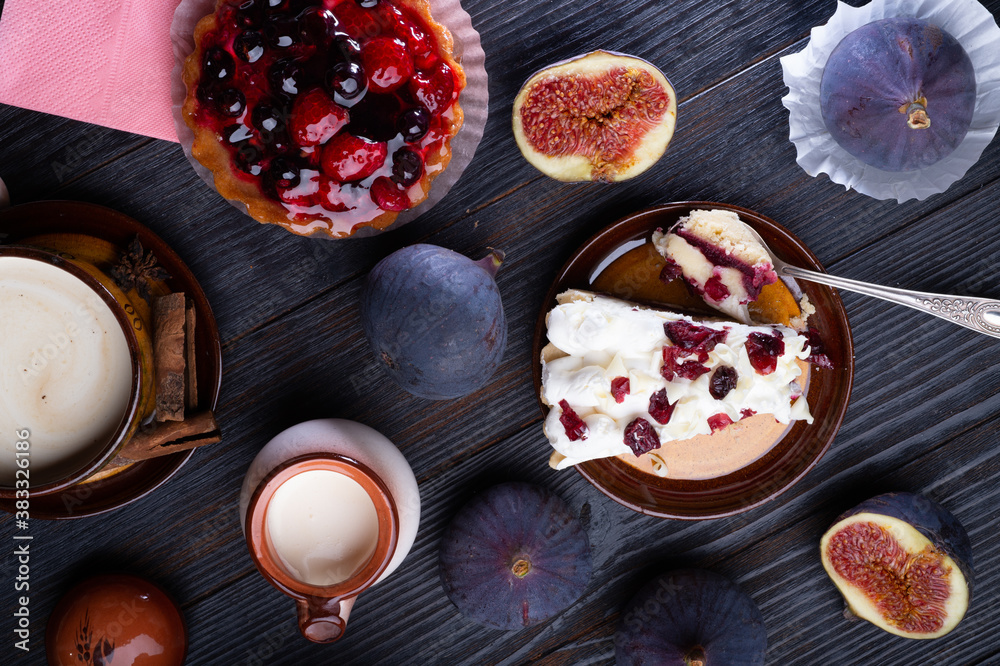 natural cream, cakes with berries and tasty ripe purple fig on black wooden table. flat lay. life style concept natural cream, cakes with berries and tasty ripe purple fig on black wooden table. flat lay. life style concept