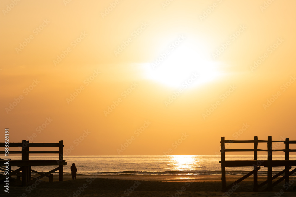 Frau steht am Nordsee Strand bei Sonnenuntergang