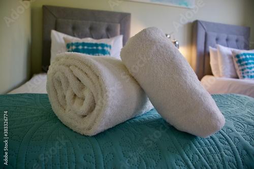 Rolled, crisp white towels sitting on a bed