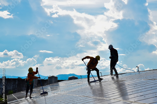 Photovoltaic installers were cleaning the top surface of photovoltaics to get and save more power to the container inside the buidlings. photo