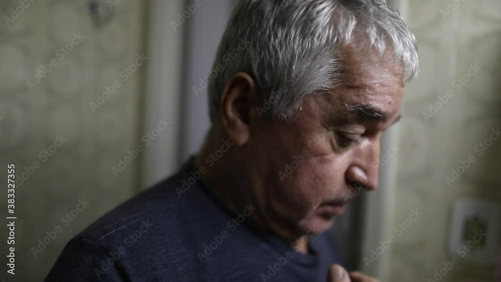 Religious older man doing the sign of the cross in front of bathroom mirror Religious older man doing the sign of the cross in front of bathroom mirror