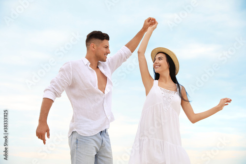 Happy young couple dancing outdoors in summer