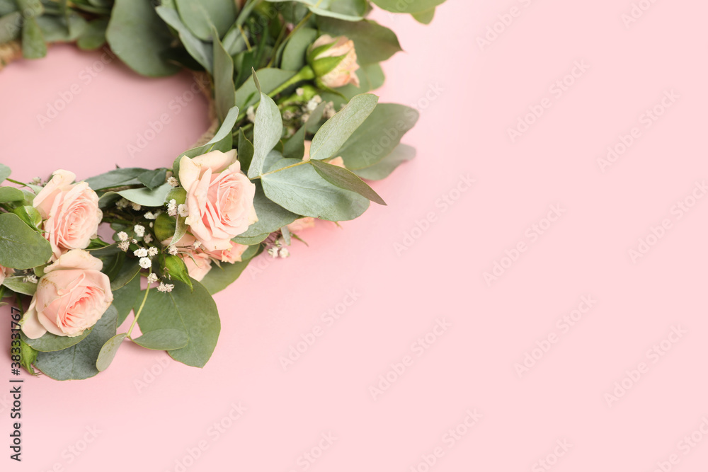 Wreath made of beautiful flowers on pink background, space for text