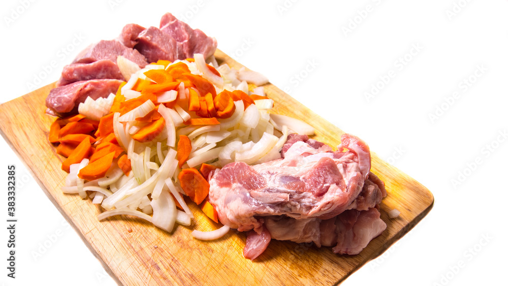 Pork meat cut into pieces with carrots and onions on a cutting Board on a white background with a place for writing,side view