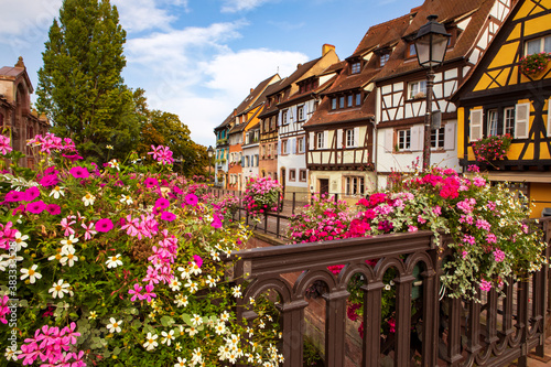 View on Colmar town with half-timbered traditional houses by the bank of the canal, flowers on the bridge. Summertime , Alsace France.