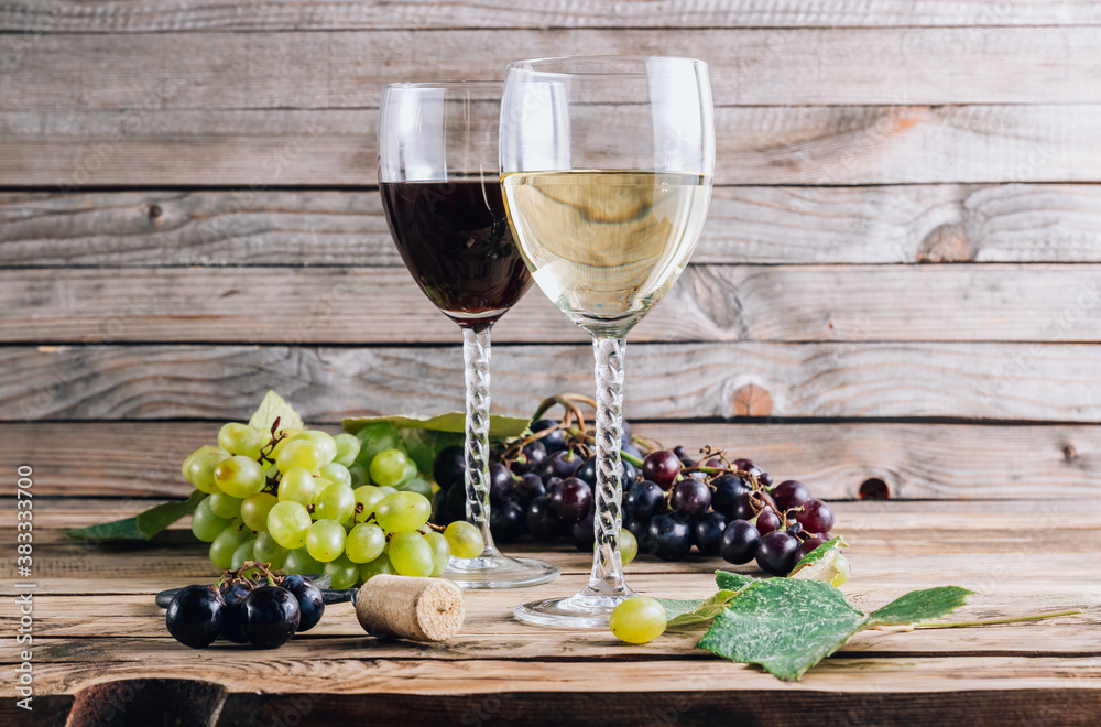 Glasses of red and white wine with grape on rustic wooden background. Selective focus