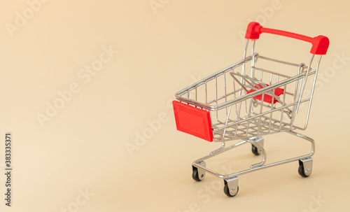 Empty red shopping cart or trolley on beige background