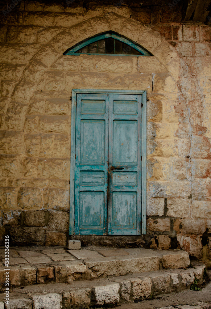 old blue wooden door in the arched stone wall