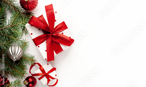 Christmas composition on a white background with white gift boxes  with a red ribbon with fir branches  toys  copy space for your congratulations
