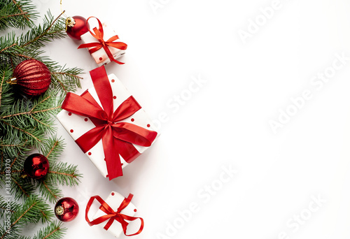 Christmas composition on a white background with white gift boxes, with a red ribbon with fir branches, toys, copy space for your congratulations