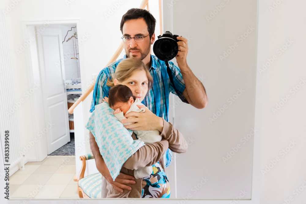 Happy parents with newborn baby taking selfie in the mirror Happy parents with newborn baby taking selfie in the mirror