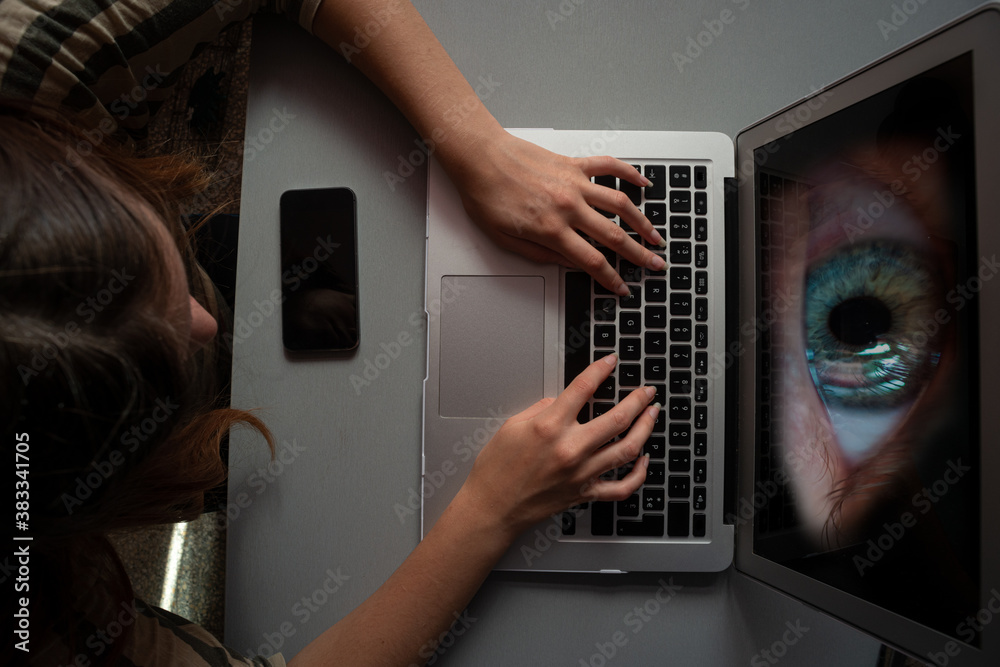 young woman using computer for shopping or work infected with spyware or malwear ,large eye watching from the screen , concept young woman using computer for shopping or work infected with spyware or malwear ,large eye watching from the screen , concept
