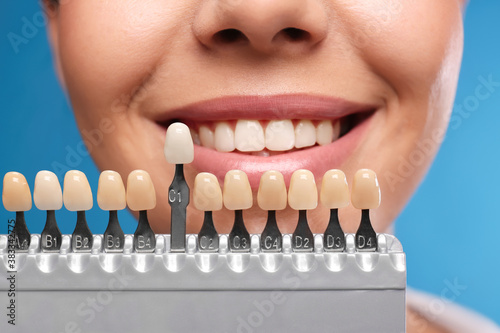 Woman checking her teeth color on blue background  closeup. Cosmetic dentistry