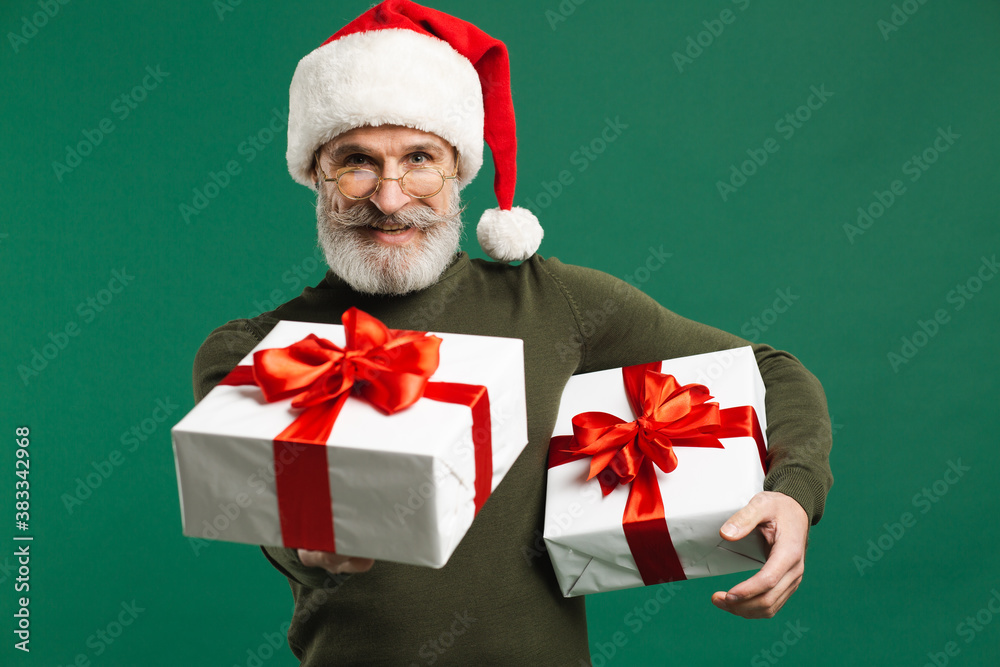 Bearded modern Santa Claus holding gifts and smiling on the green background Bearded modern Santa Claus holding gifts and smiling on the green background