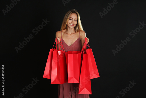 Happy young woman with shopping bags on dark background. Black Friday Sale