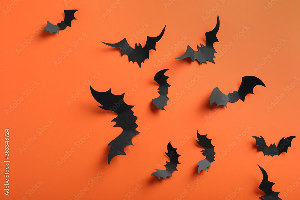 Paper bats on orange background, flat lay. Halloween decor