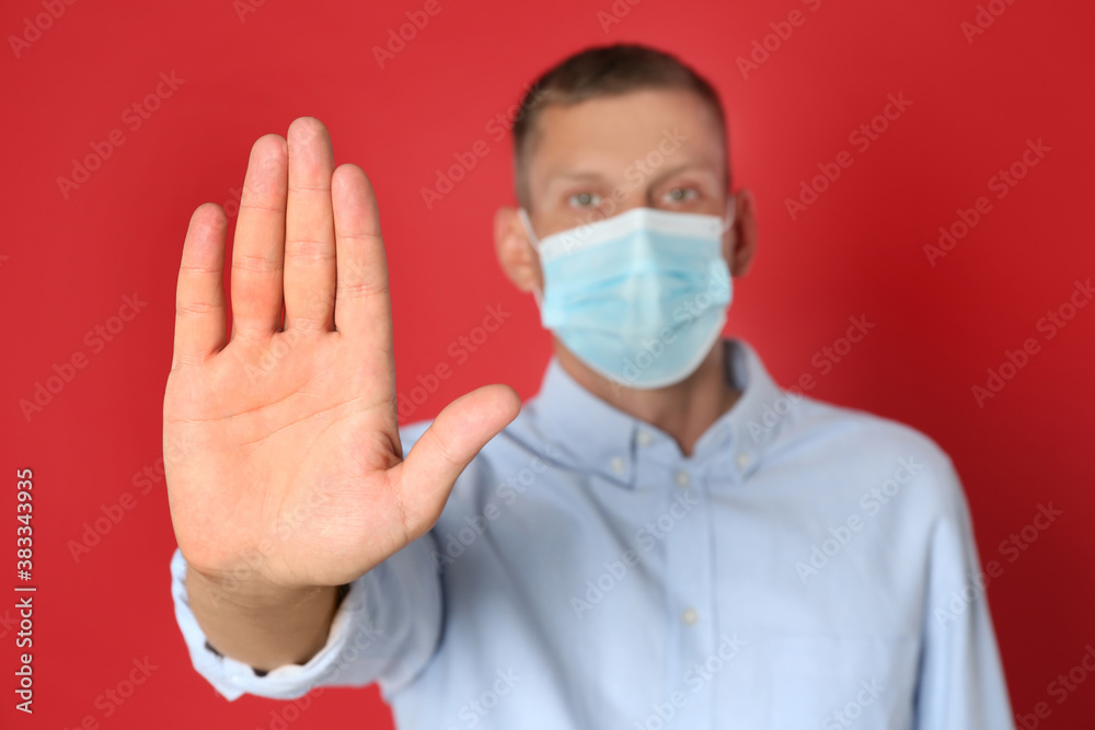 Man in protective mask showing stop gesture on red background. Prevent spreading of coronavirus Man in protective mask showing stop gesture on red background. Prevent spreading of coronavirus