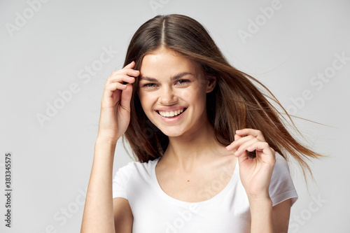 Happy woman removes hair from her face and smiles in a white T-shirt 