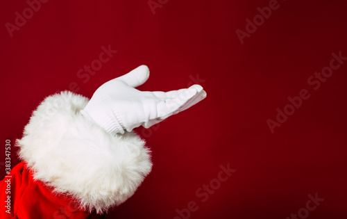 Close up photo of Santa Claus hand in white glove isolated on red background