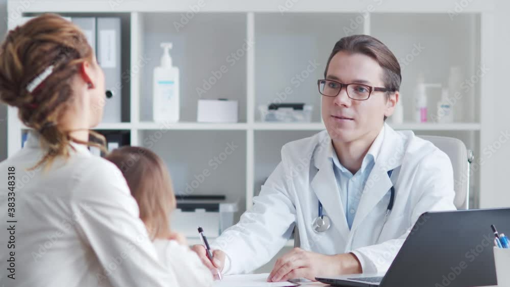 Male pediatrician is examining sick little baby. Doctor, mother and daughter in medical office in clinics. Male pediatrician is examining sick little baby. Doctor, mother and daughter in medical office in clinics.