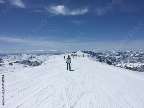 Skiers and snowboarders on a high ridge at a ski resort on a sunny winter day
