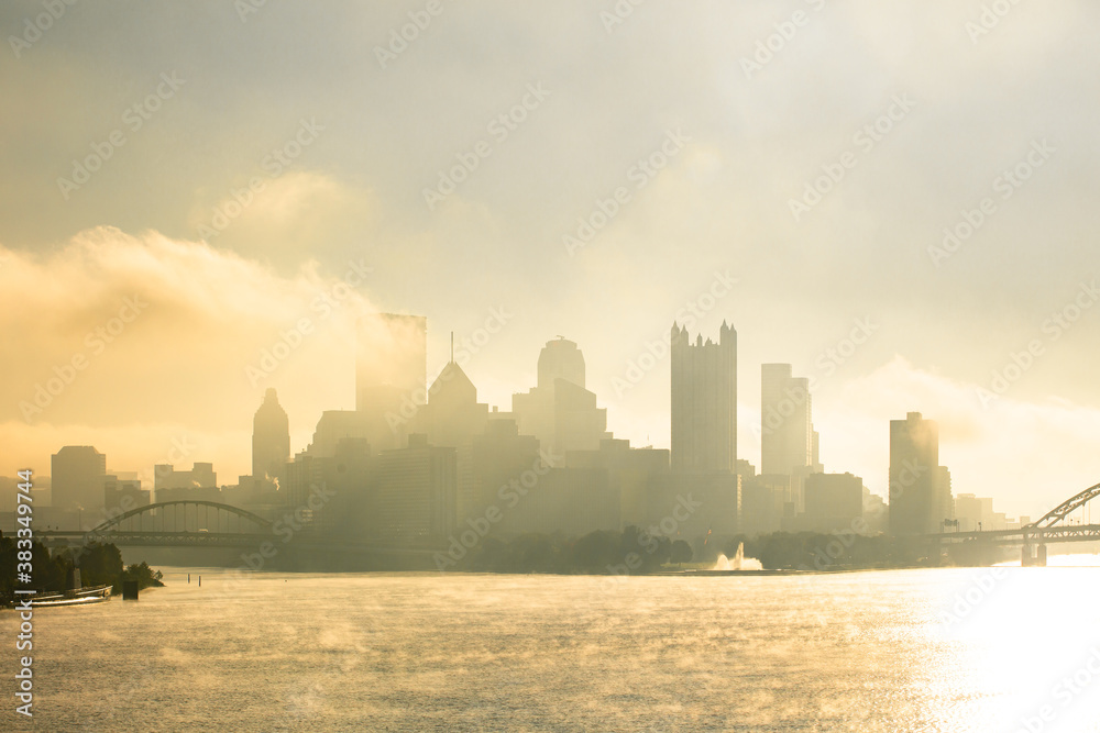 A foggy, misty morning over the Pittsburgh Ohio river with bridges and urban buildings and infrastructure.