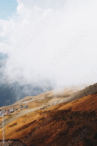 Cloudy day in mountains, clouds descend from the mountains to the village from above. descent by cable car