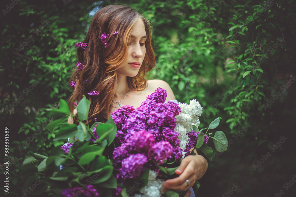 A young woman is holding a beautiful bouquet of lilacs.The girl's hair is loose.Flowers in your hair. A young woman is holding a beautiful bouquet of lilacs.The girl's hair is loose.Flowers in your hair.
