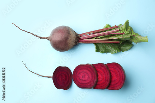 Whole and cut fresh red beets on light blue background, flat lay
