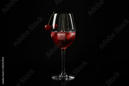 Delicious cherry wine with ripe juicy berries on black background