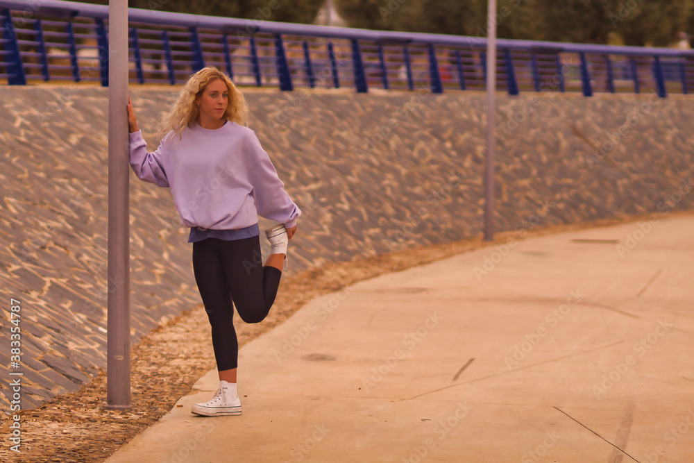 Young blonde woman doing stretching to start running. Young blonde woman doing stretching to start running.