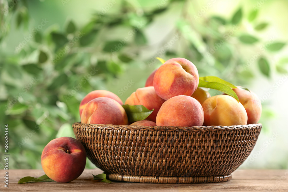 Fresh sweet peaches in wicker basket on wooden table outdoors