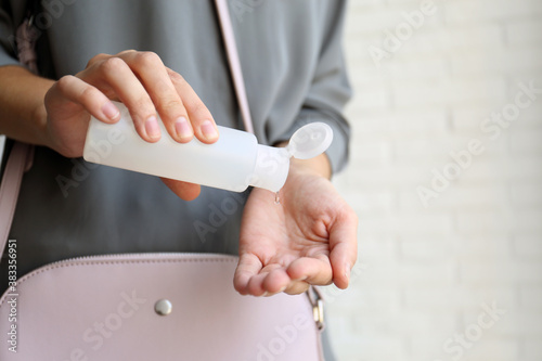 Woman applying hand sanitizer on light background, closeup. Personal hygiene during COVID-19 pandemic