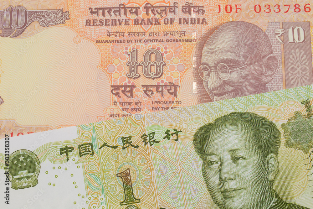 A macro image of a orange ten rupee bill from India paired up with a green and white one yuan note from China.  Shot close up in macro.