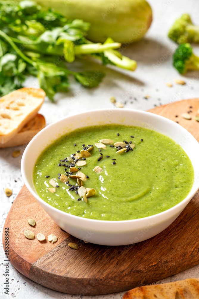 Green vegetable cream soup in a white bowl on a gray concrete background. Vegan soup puree of green vegetables. Vegetarian and diet food. Green vegetable cream soup in a white bowl on a gray concrete background. Vegan soup puree of green vegetables. Vegetarian and diet food.