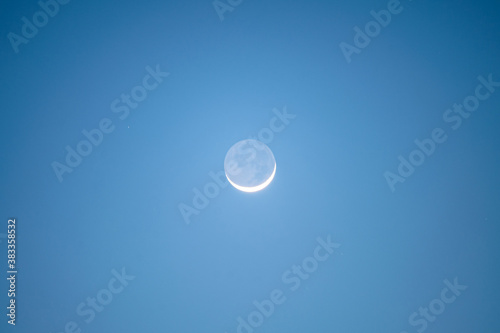 Crescent moon glowing in blue sky