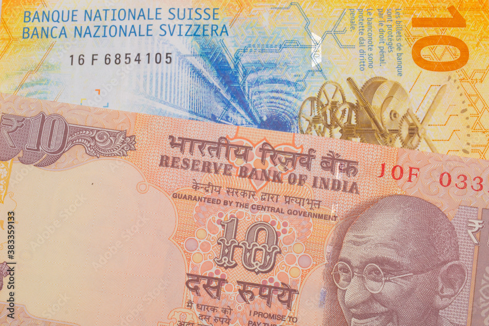 Fototapeta premium A macro image of a orange ten rupee bill from India paired up with a yellow Swiss ten franc bill. Shot close up in macro.