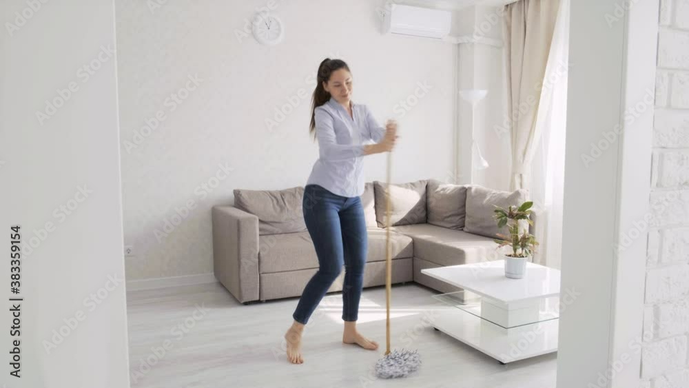 A girl dances and sings with a mop while cleaning. Good mood. A young woman is cleaning. Positive thinking. Dancing during cleaning A girl dances and sings with a mop while cleaning. Good mood. A young woman is cleaning. Positive thinking. Dancing during cleaning