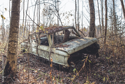 old car abandoned in the forest/abandoned old car littering the forest