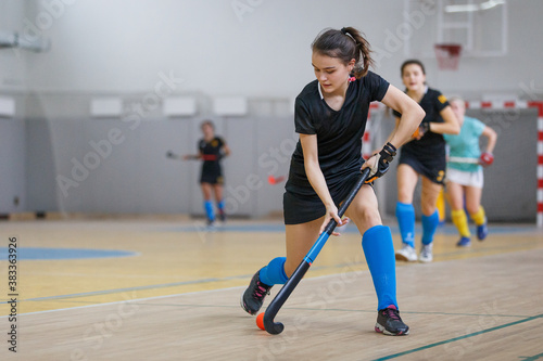 Obraz na plátně Young woman player in attack at indoor hockey match