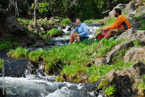 Hiker couple resting by a cold mountain stream