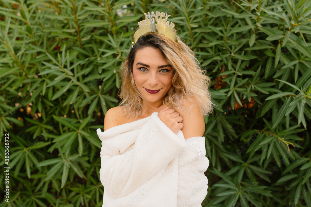 Young blonde attractive woman in red dress and white coat with New Year's Eve crown on a green background.
Young blonde attractive woman in red dress and white coat with New Year's Eve crown on a green background.