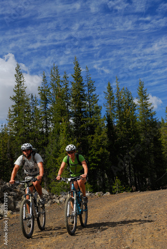 A couple of mountain bikers on dirt road with blue sky